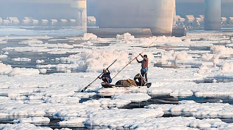 A man rows a boat through toxic foam floating on the Yamuna River at Kalindi Kunj, in New Delhi.