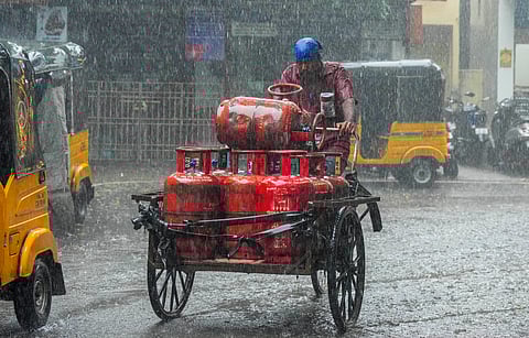 An LPG cylinder delivery man caught in a sudden rain, in Chennai, Wednesday, Oct. 30, 2024.