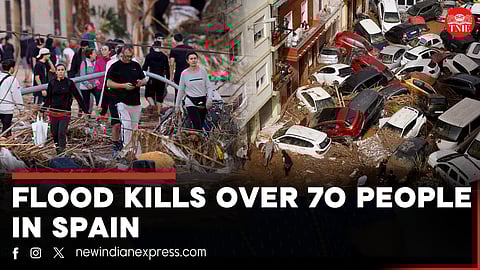 A man stands next to flooded cars piled up in Valencia, Spain, Thursday, Oct. 31, 2024.