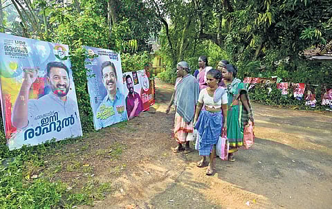 Women workers on their way to farms look at colourful flex boards of candidates at Mathur in Palakkad assembly constituency 
