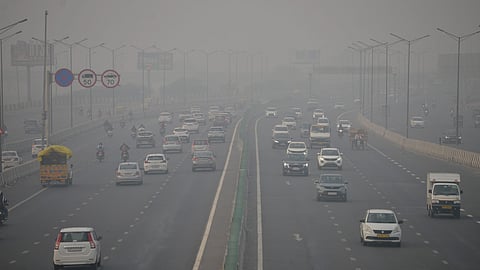 Vehicles ply on the road amid low-visibility due to smog, in New Delhi, Thursday.
