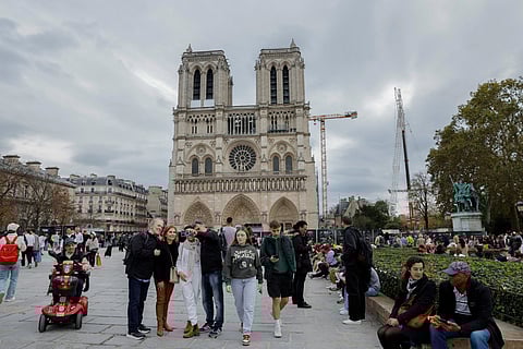 Visitors wander in front of Notre-Dame de Paris Cathedral in Paris on October 25, 2024, which is due to reopen to the public on December 8, 2024. 