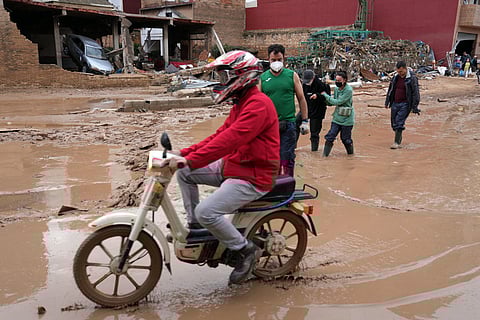 People try to walk on a street covered in muddy water in Catarroja, region of Valencia, eastern Spain, on November 8, 2024