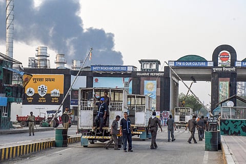 Workers wait outside after an explosion at a refinery of Indian Oil Corporation, in Vadodara, Monday, Nov. 11, 2024