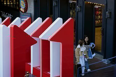 Women walk out from a fashion boutique near a display promoting the China popular e-commerce sales, the "Singles' Day" global online shopping festival, at a shopping mall in Beijing.