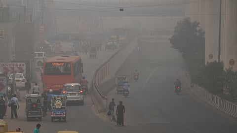 Vehicles ply on the road amid low-visibility due to fog, in New Delhi.