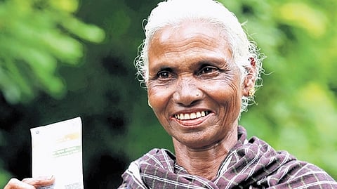 A voter from Bavali village displays her Aadhaar card after casting her vote