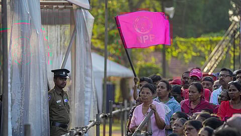 A woman holds a flag of Sri Lankan President Anura Kumara Dissanayake 's National People's Power party during a public rally ahead of Thursday's parliamentary election in Gampaha, Sri Lanka.
