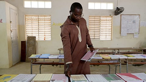 A man picks up ballot at a polling station in Dakar on November 17, 2024, during Senegal's parliamentary elections
