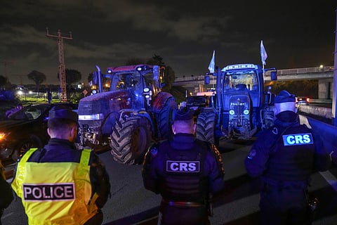 Police officers stand in front of tractors on a blocked highway in Velizy-Villacoublay, outside Paris, Sunday, Nov. 17, 2024