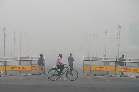 A man cycles near the India Gate amid low visibility due to smog as air quality remains in 'severe' category, in New Delhi, Monday, Nov. 18, 2024.