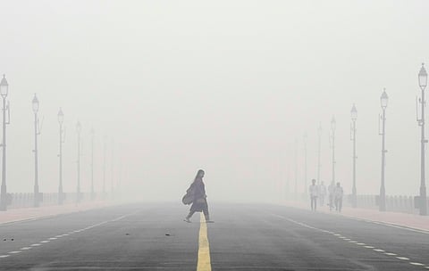 A woman crosses the Kartavya Path amid low visibility due to smog as air quality remains in 'severe' category, in New Delhi on Monday.