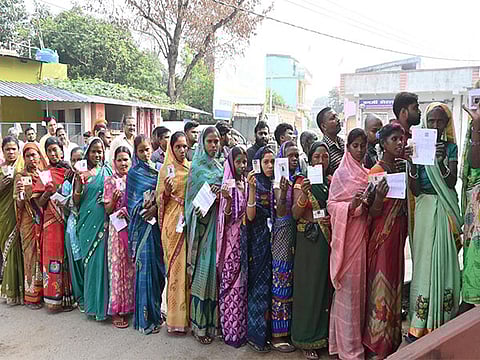 Voters show their IDs while waiting in queues to cast their vote for the second and final phase of the Jharkhand Assembly elections, in Ranchi.