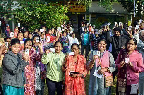 Voters show their IDs while waiting in queues to cast their vote for the second and final phase of the Jharkhand Assembly elections, in Ranchi.