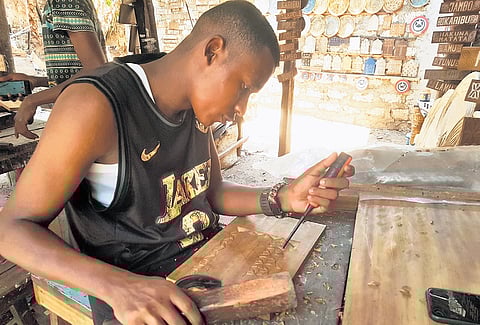 A wood carver crafts a dhow
