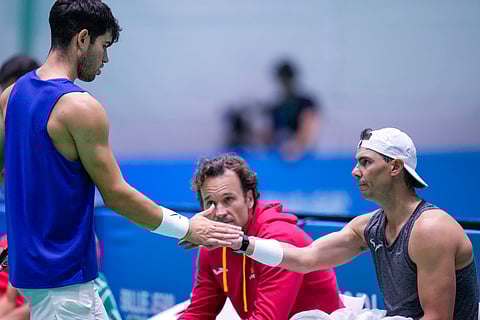 Spain's Carlos Alcaraz, left, shakes hands with Rafael Nadal during a training session at the Martin Carpena Sports Hall, in Malaga, southern Spain.