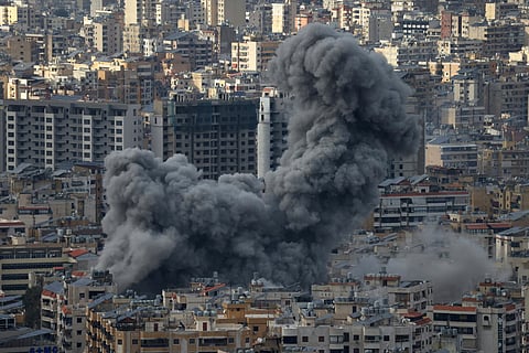Residents pass in front of a destroyed building that was hit Sunday night in an Israeli airstrike in Dahiyeh, in the southern suburb of Beirut, Lebanon.
