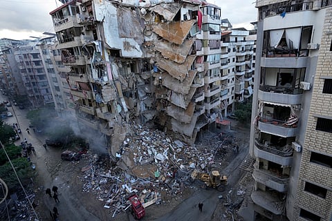 Residents pass in front of a destroyed building that was hit Sunday night in an Israeli airstrike in Dahiyeh, in the southern suburb of Beirut, Lebanon.