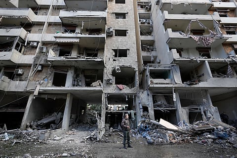 Residents pass in front of a destroyed building that was hit Sunday night in an Israeli airstrike in Dahiyeh, in the southern suburb of Beirut, Lebanon.