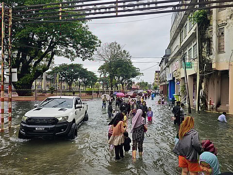 Residents walk on a flooded street after heavy monsoon rains in downtown Kota Bharu, Kelantan, Malaysia on Friday.