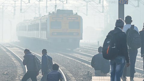 Commuters at Tilak Bridge Railway Station amid low visibility on Monday.