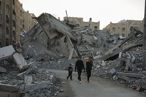 Young Palestinians walk amongst rubble of destroyed buildings at a neighbourhood in Khan Younis, Gaza Strip, Sunday, Dec. 1, 2024. 
