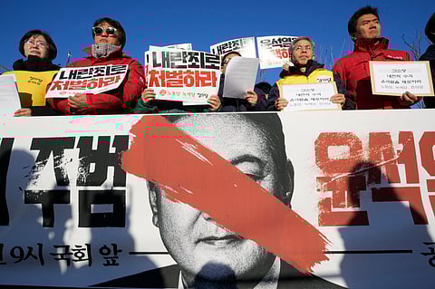 Protesters stage a rally to demand South Korean President Yoon Suk Yeol to step down in front of the National Assembly in Seoul, South Korea, Wednesday, Dec. 4, 2024. The signs read "Punish.".