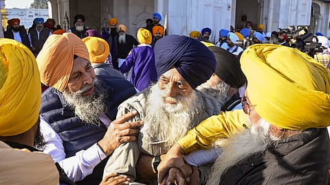 People catch a man, center, who allegedly opened fire at Shiromani Akali Dal leader Sukhbir Singh Badal while the latter was performing the duty of 'sewadar' outside the Golden Temple, in Amritsar.