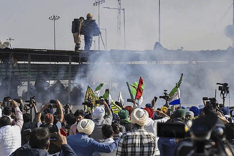 Farmers run for cover after police used teargas to disperse them during their protest at the Shambhu border, in Patiala district, Sunday, Dec. 8, 2024.