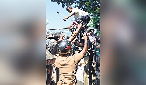 Policemen pushing a KSU worker when he tried to scale the barricade erected in front of the University College.
