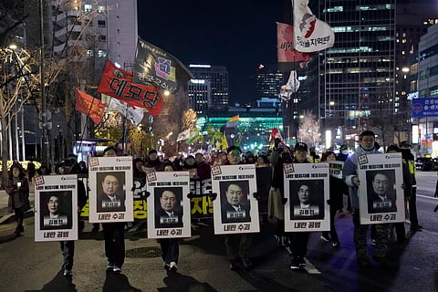 Protesters hold a banner showing images of impeached President Yoon Suk Yeol, right, and acting President Han Duck-soo during a rally demanding the arrest of Yoon in Seoul, South Korea, Saturday, Dec. 21, 2024. The banner reads "Denounce Han Duck-soo's veto