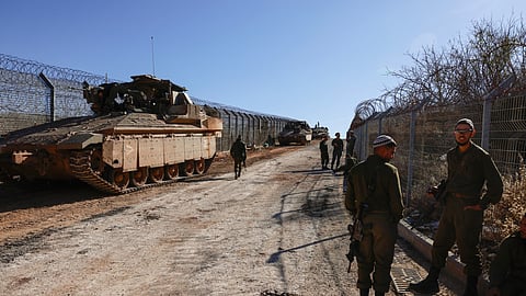 Israeli soldiers stand on the fence with the buffer zone that separates the Israeli-annexed Golan Heights from Syria, on December 9, 2024, near the Druze village of Majdal Shams.