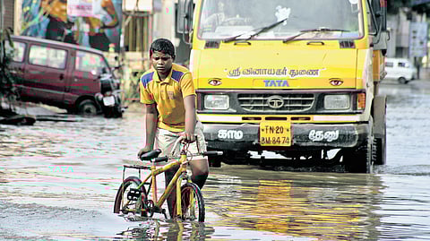 A boy pushing his bicycle through an inundated Teachers Colony
Main Road in Kolathur, Chennai during the floods in 2015. 