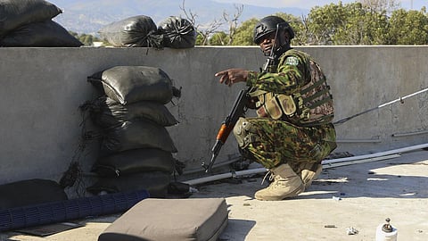 A Kenyan police officer, part of a UN-backed multinational force, kneels for cover.