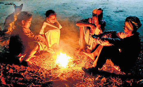 People warn themselves by a bonfire on a cold Thursday morning in Karimnagar