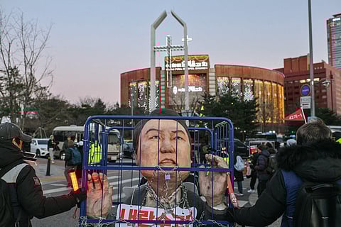 Protesters hold a banner showing images of impeached President Yoon Suk Yeol, right, and acting President Han Duck-soo during a rally demanding the arrest of Yoon in Seoul, South Korea, Saturday, Dec. 21, 2024. The banner reads "Denounce Han Duck-soo's veto
