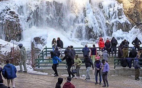 Tourists visit a frozen waterfall at Drung area on a cold winter morning, in Baramulla district, Jammu and Kashmir.