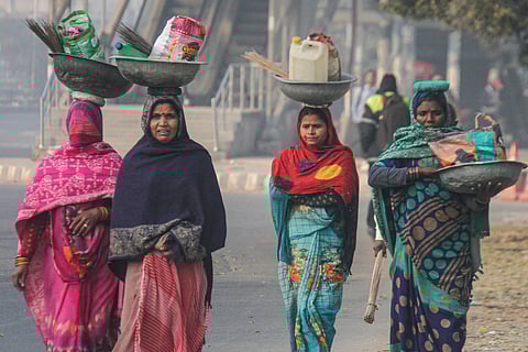 Women walk on a road during a cold winter morning, in Gurugram on Saturday. 