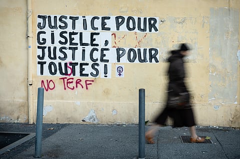 A pedestrian walks past a collage mural reading "Justice for Gisele, Justice for all" near the Avignon courthouse where the Mazan rape trial is taking place in Avignon.