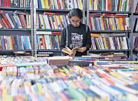 A girl browse a book at a stall in the Hyderabad Book Fair at NTR Stadium on its inauguration day on Thursday