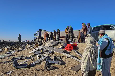 Afghan residents inspect the accident site as they stand near the remains of a bus following its collision with a coal truck on a highway between Kabul and southern Kandahar city, in the Andar district of Ghazni province, on December 19, 2024.