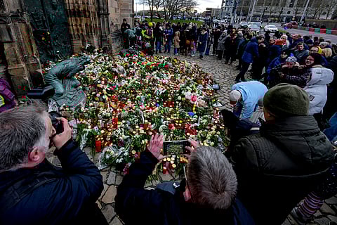 People lay flowers at the entrance of a church near a Christmas Market, where a car drove into a crowd on Friday evening, in Magdeburg, Germany, Saturday, Dec. 21, 2024.