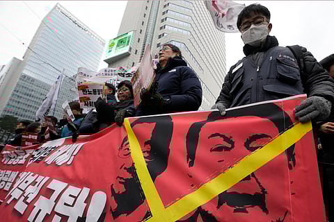 Protesters hold a banner showing images of impeached President Yoon Suk Yeol, right, and acting President Han Duck-soo during a rally demanding the arrest of Yoon in Seoul, South Korea, Saturday, Dec. 21, 2024. The banner reads "Denounce Han Duck-soo's veto