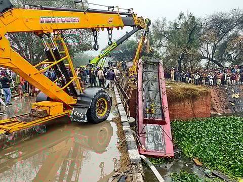 A crane pulls the wreckage of a bus that fell into a drain after an accident, in Bathinda, Friday, Dec. 27, 2024.