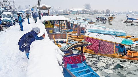 A visitor takes pictures at Dal Lake after the season’s first snowfall in Srinagar.