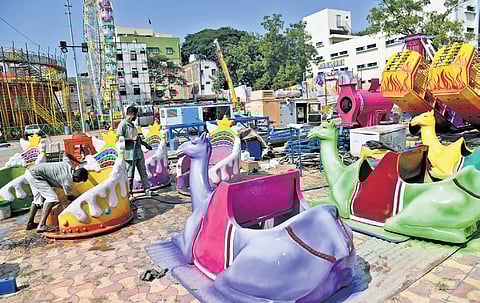 Workers clean and prepare amusement park rides, bringing vibrant life to the fairground of Numaish in Nampally.