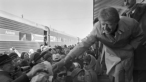 President-elect Jimmy Carter leans over to shake hands with some of the people riding the "Peanut Special" to Washington, Jan. 19, 1977. 