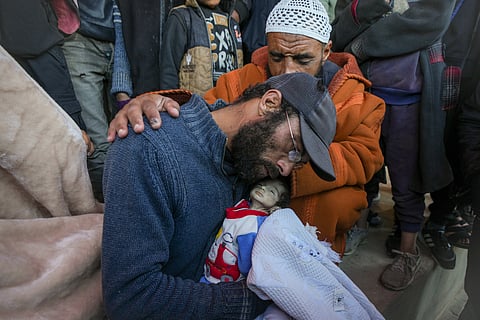 Yehia al-Batran grieves as he holds the body of his 20-day-old son Jomaa, who died from hypothermia, at Al-Aqsa Martyrs Hospital in central Gaza, Sunday