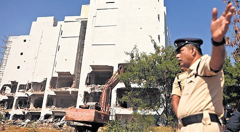 Police personnel guard the demolition site as a crane razes the unauthorised building in Hyderabad on Sunday