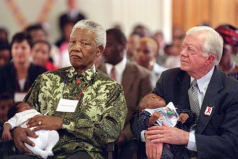 Former South African President Nelson Mandela, left, and former U.S. President Jimmy Carter, right, hold HIV-positive babies at the Zola Clinic in Soweto, March 7, 2002.